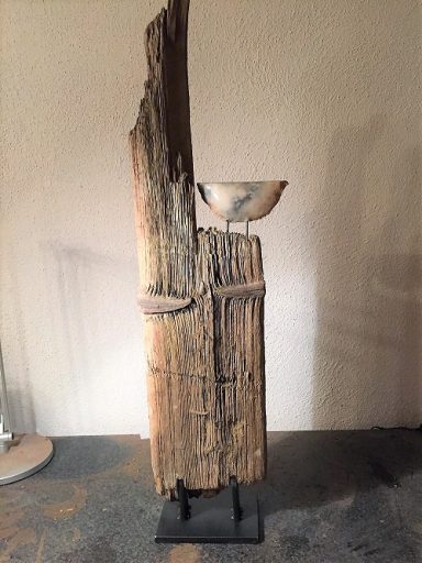 Skulptur aus Holz mit einem keramischen stilisierten Boot auf einem Standfuß.