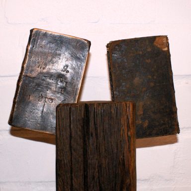 Ein Buch aus Bronze und ein altes, abgenutztes Buch auf einem Holz.