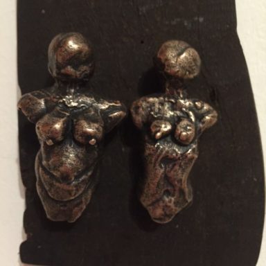 Zwei kleine, kunstvoll gestaltete Metallfiguren menschlicher Körperformen.