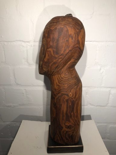 Holzfigur in menschlicher Form, seitlich betrachtet, mit detaillierter Maserung.